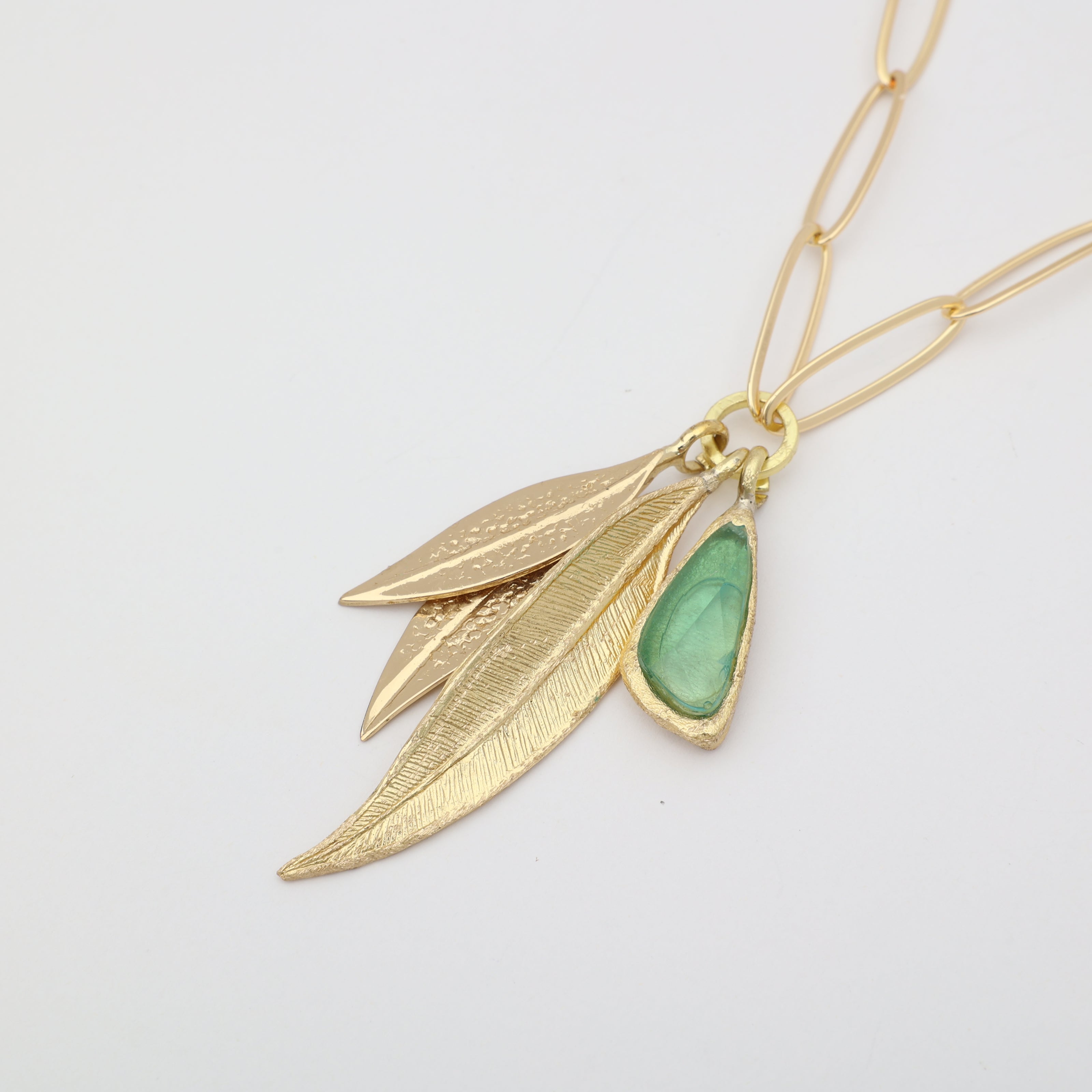 Handmade brass charm necklace with sculptural leaf pendants and resin stone on paperclip chain
