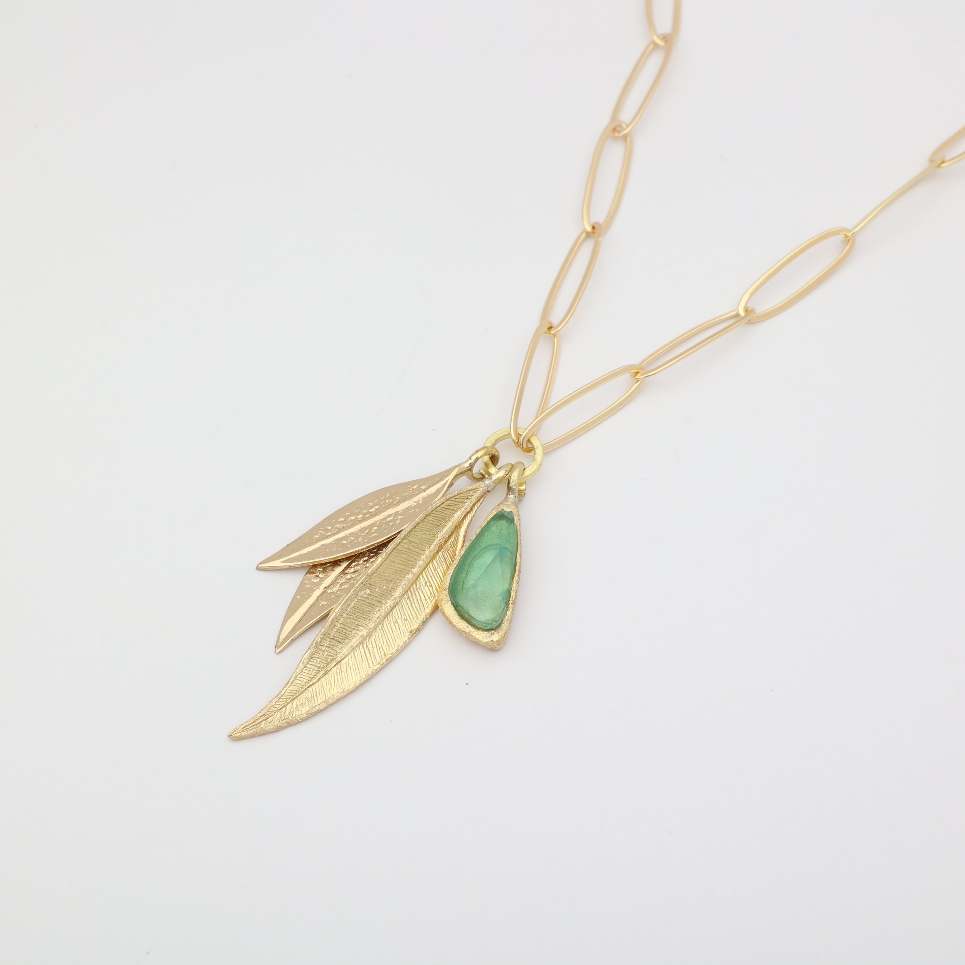 Handmade brass layered leaf and resin stone charm necklace, close-up detail on white background

