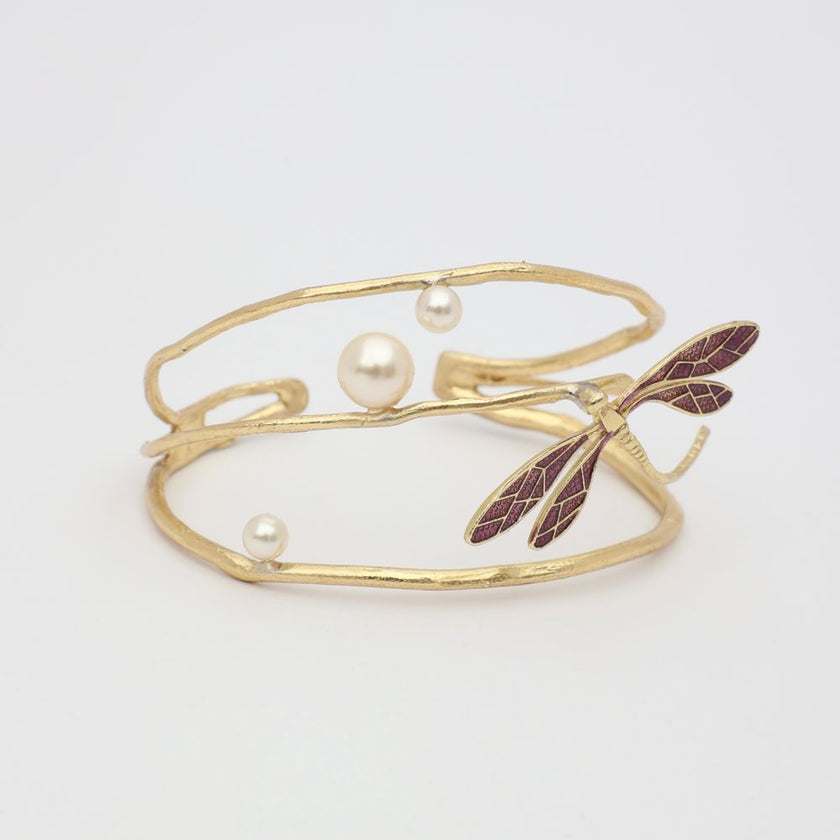 Gold bracelet with pearl beads and leaf design on a white background