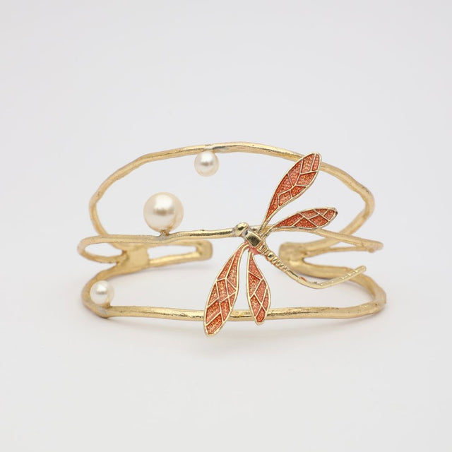 Gold bracelet with dragonfly and pearl design on a light gray background