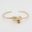handmade brass open cuff with textured shell centerpiece and crystal detail on white background
