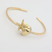 Tide Bracelet — handmade brass open cuff with sculpted shell and starfish motif on white background