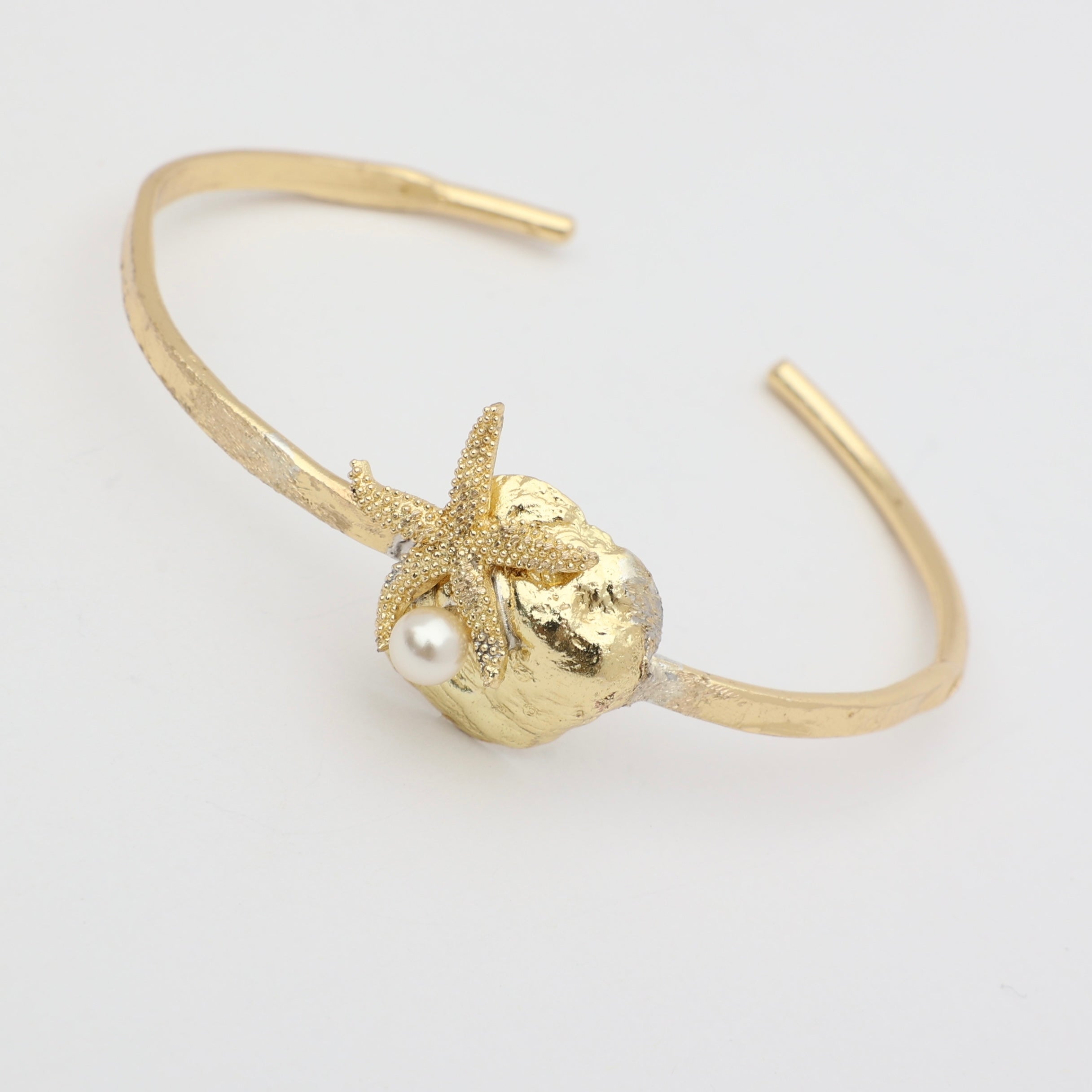 Tide Bracelet — handmade brass open cuff with sculpted shell and starfish motif on white background
