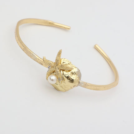 Tide Bracelet — handmade brass open cuff with sculpted shell and starfish motif on white background