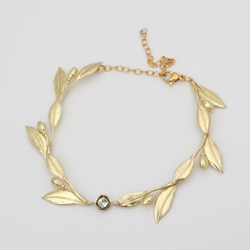 Handmade brass sculptural leaf bracelet with crystal accent on white background
