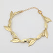 Handmade brass sculptural leaf and fruit bracelet on white background

