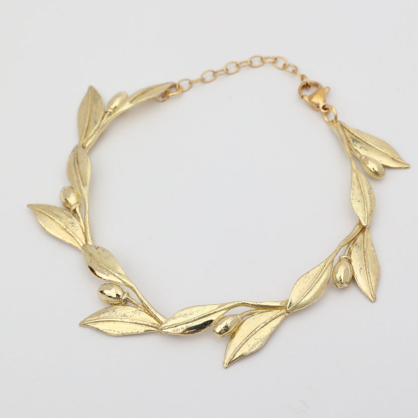 Handmade brass sculptural leaf and fruit bracelet on white background
