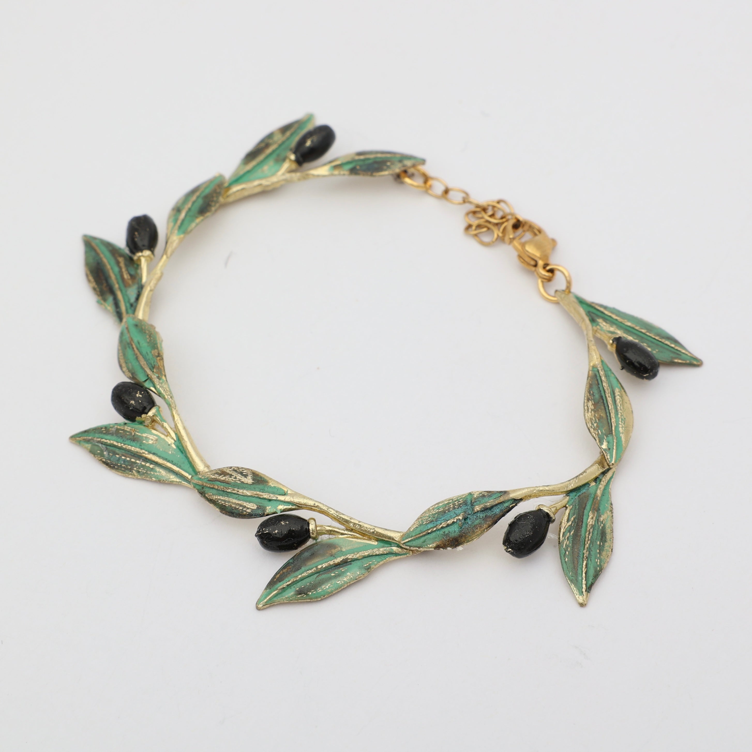 Handmade brass botanical branch bracelet with continuous leaf motif, flat lay