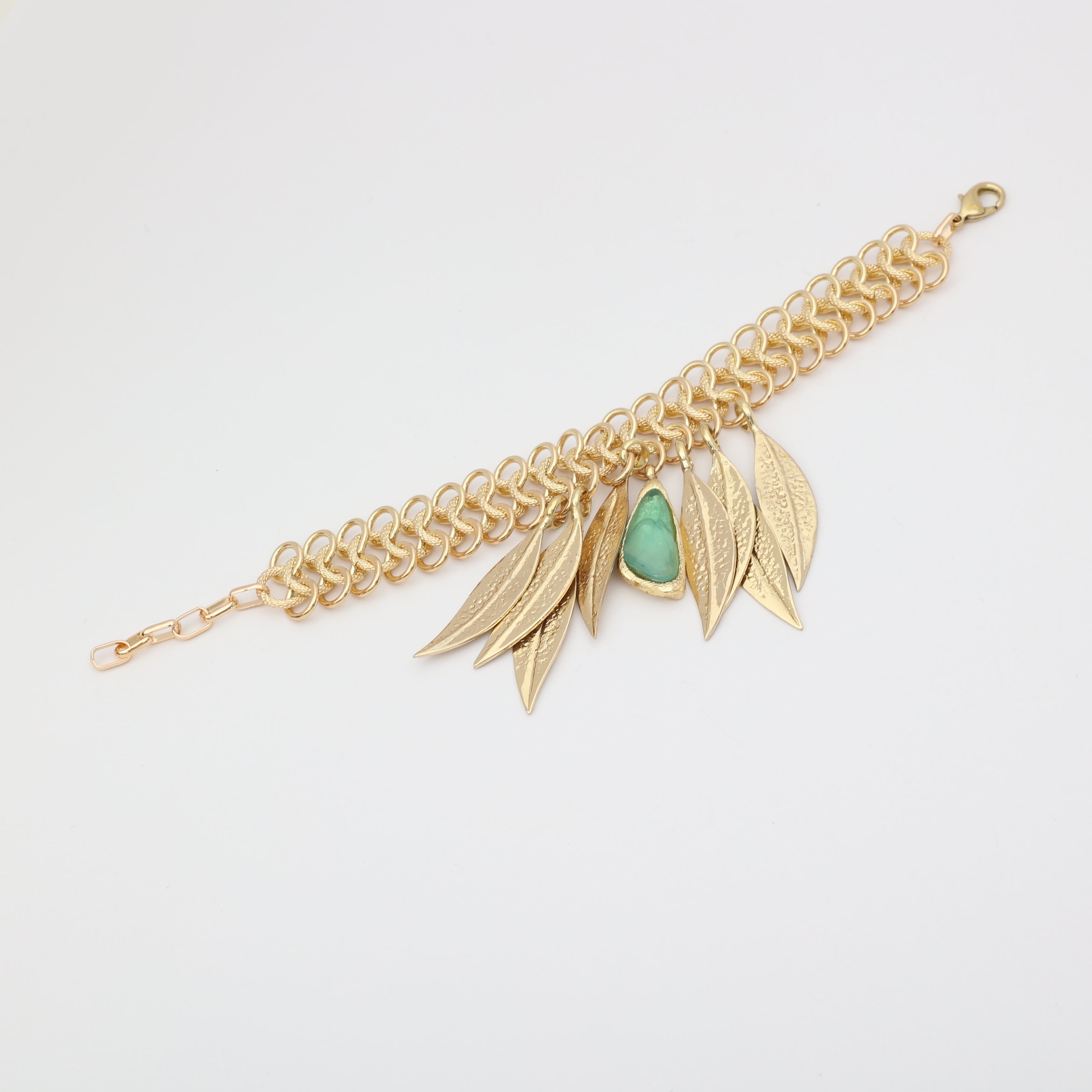 Handmade brass statement bracelet with fringe leaf drops and resin stone centerpiece, flat lay
