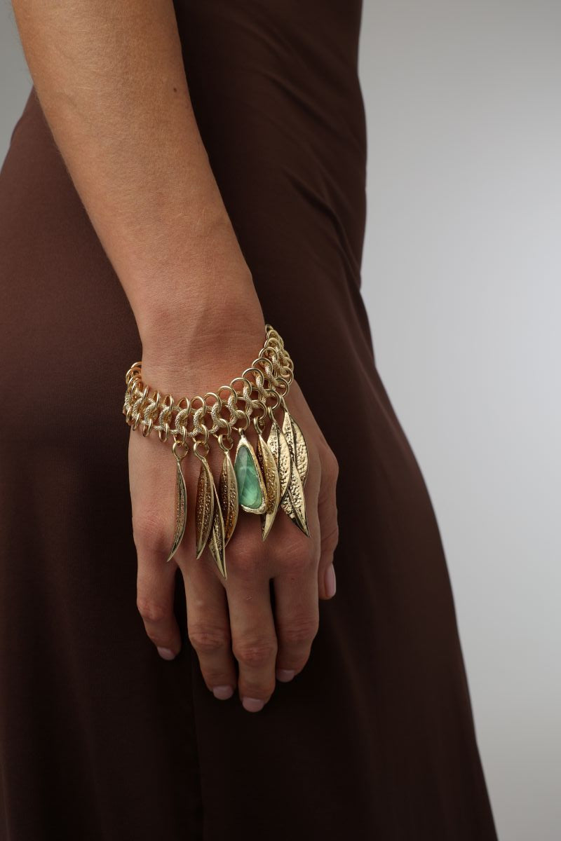 Handmade brass woven chainmail bracelet with dangling leaf and resin stone charm, close-up
