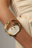 Crasta Bracelet close-up — handmade brass open cuff with textured crab legs and organic resin stone centerpiece
