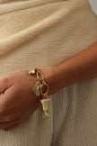 Icon Bracelet close-up — handmade brass charm bracelet with Greek goddess and column charms on model