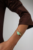 Handmade brass open cuff bracelet with leaf motif and resin stone worn on wrist
