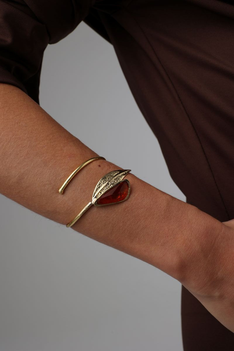 Handmade brass sculptural bangle with raw stone and tapered leaf end, side view on model
