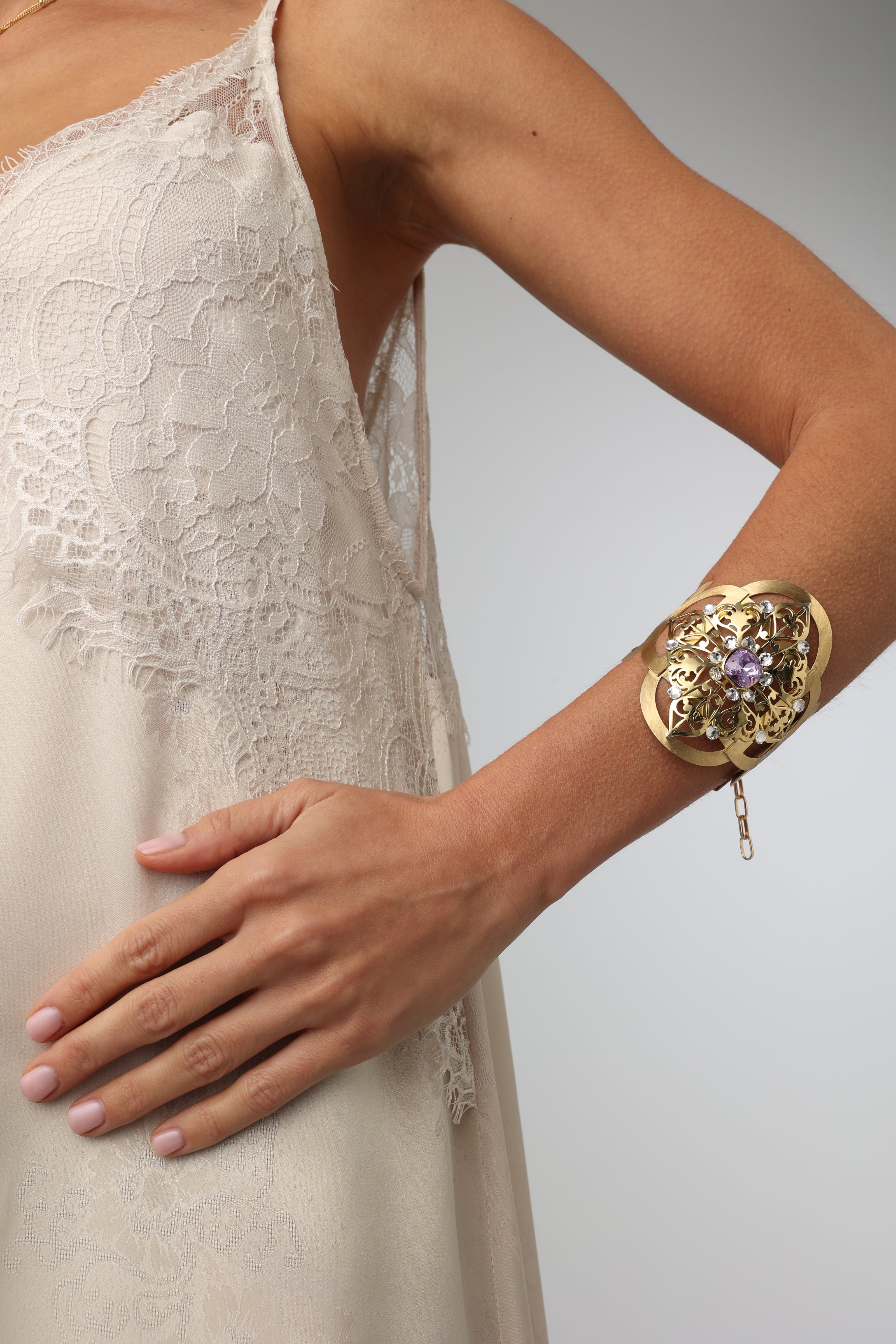 Model wearing a handmade Greek brass filigree cuff bracelet with a purple crystal.