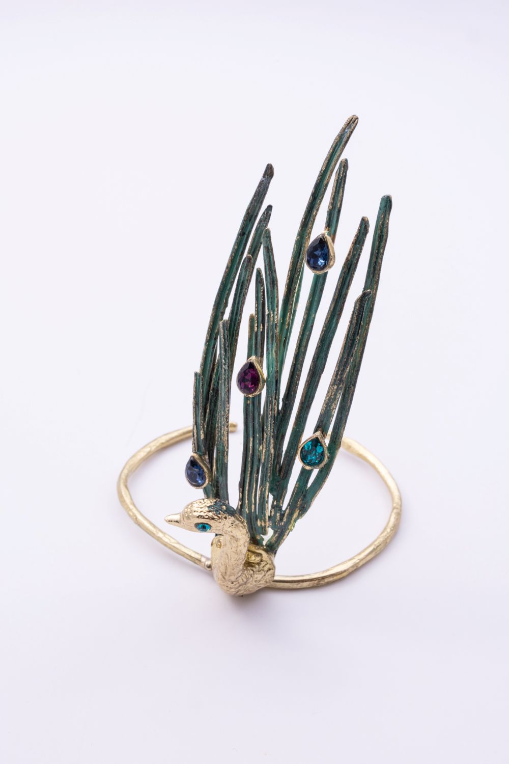 Peacock statement cuff bracelet with green patina feathers and multicolor crystals, front view on white background