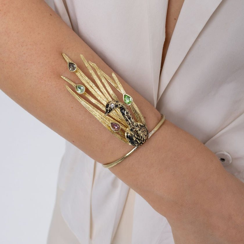 Woman wearing the gold Peacock cuff bracelet with green, pink and mint teardrop crystals,