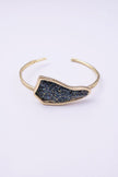 Edge handmade gold-plated brass cuff bracelet with crystal-encrusted iridescent plate on a white background