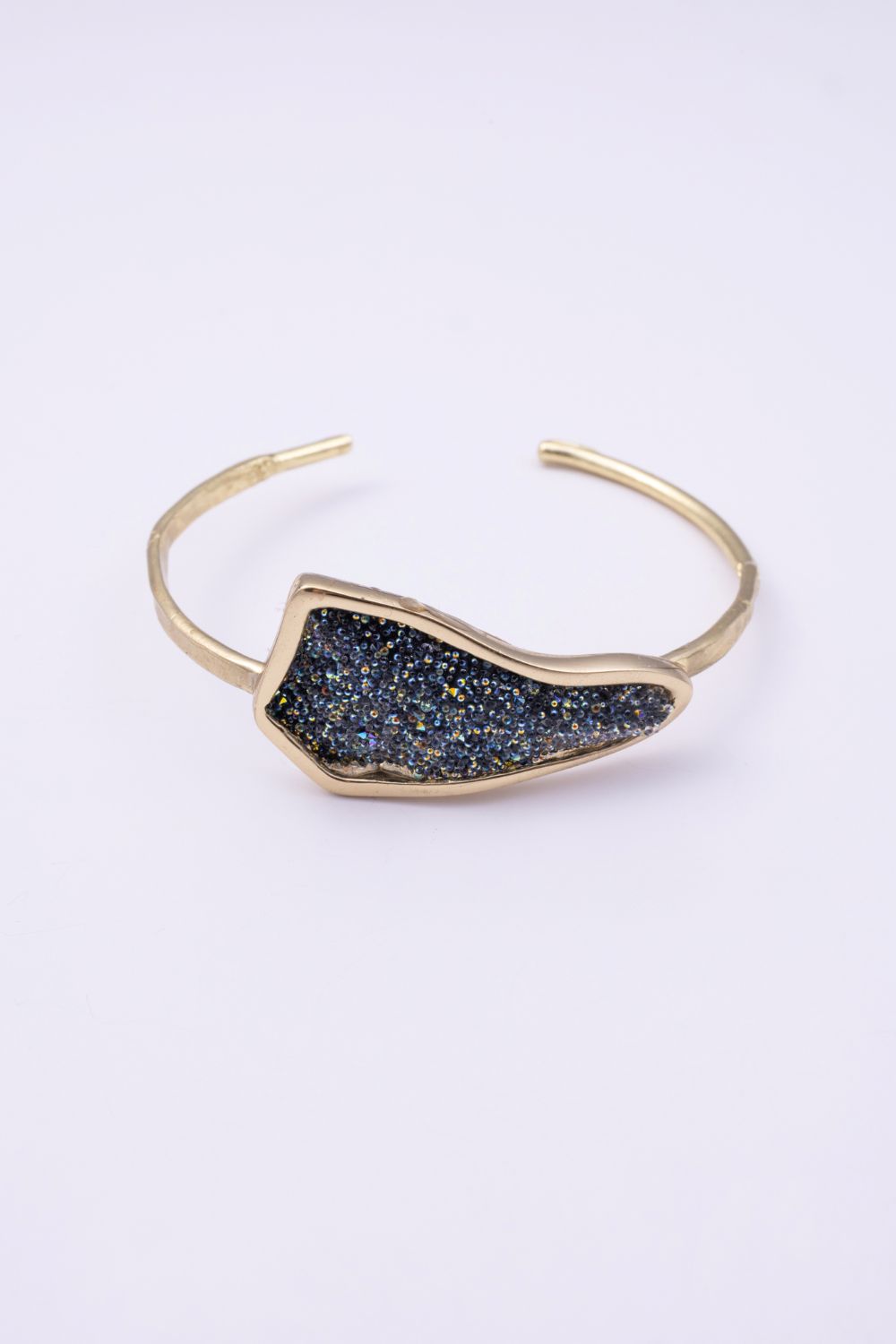 Edge handmade gold-plated brass cuff bracelet with crystal-encrusted iridescent plate on a white background