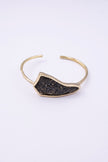 Edge handmade gold cuff bracelet with black crystal pavé plate and hammered open band on a white background