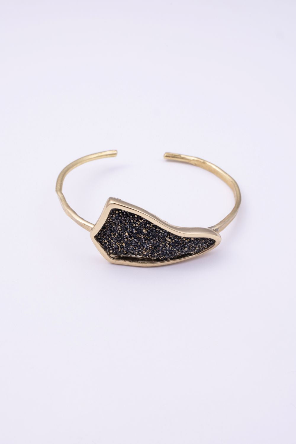 Edge handmade gold cuff bracelet with black crystal pavé plate and hammered open band on a white background