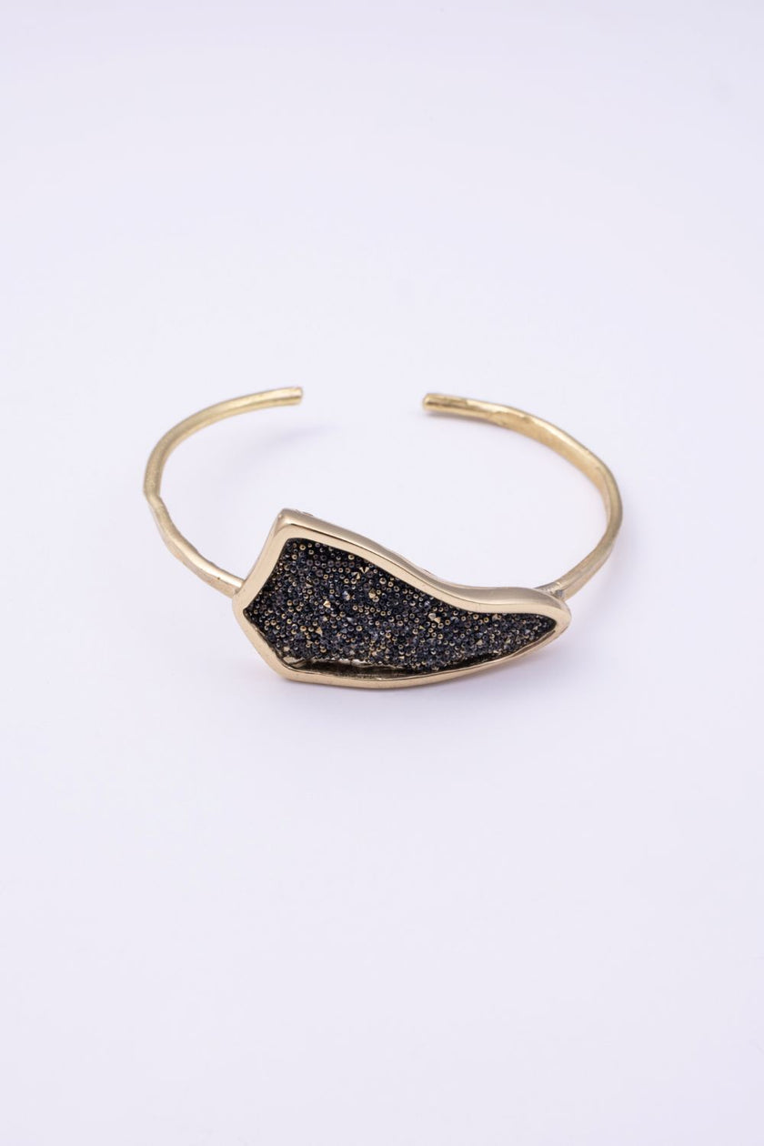 Edge handmade gold cuff bracelet with black crystal pavé plate and hammered open band on a white background