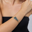 Woman wearing the Edge gold-plated cuff bracelet with a sculptural plate of iridescent blue crystals, Glitter Kiss