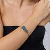 Woman wearing the Edge gold-plated cuff bracelet with a sculptural plate of iridescent blue crystals, Glitter Kiss