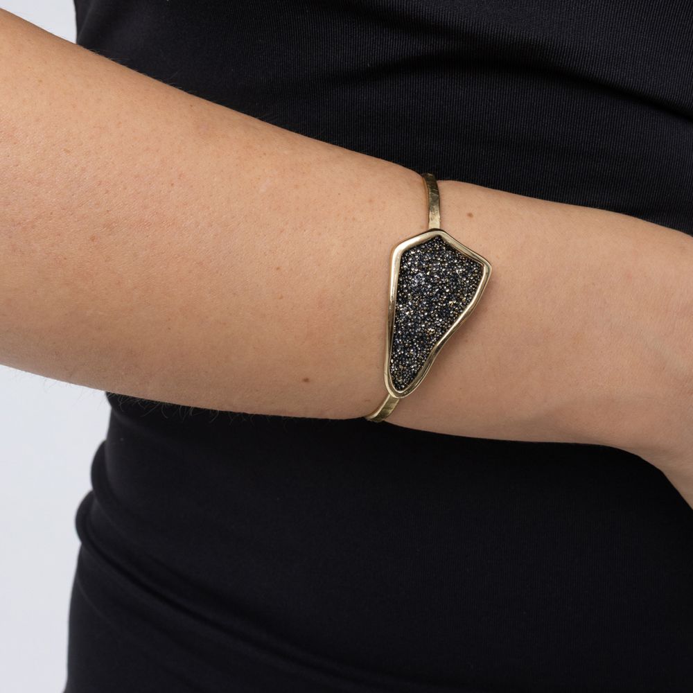 Woman wearing the Edge gold-plated cuff bracelet with a dark hematite crystal-encrusted plate, Glitter Kiss