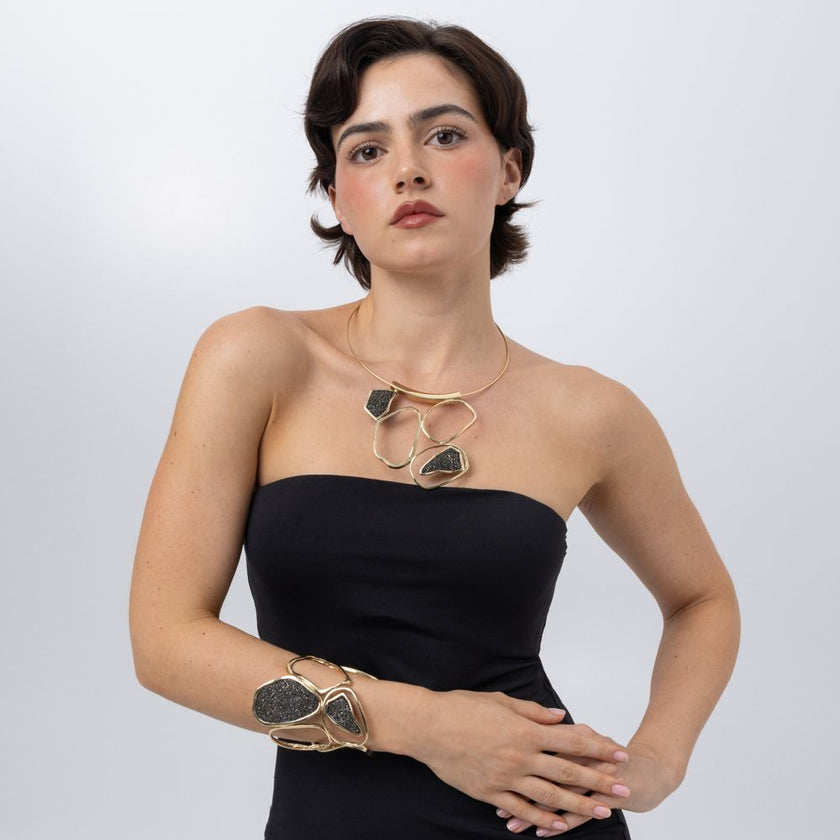 Model wearing Glitter Kiss gold statement cuff and sculptural crystal necklace