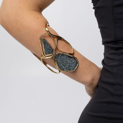 Sculptural gold statement cuff with crystal panels worn on the forearm