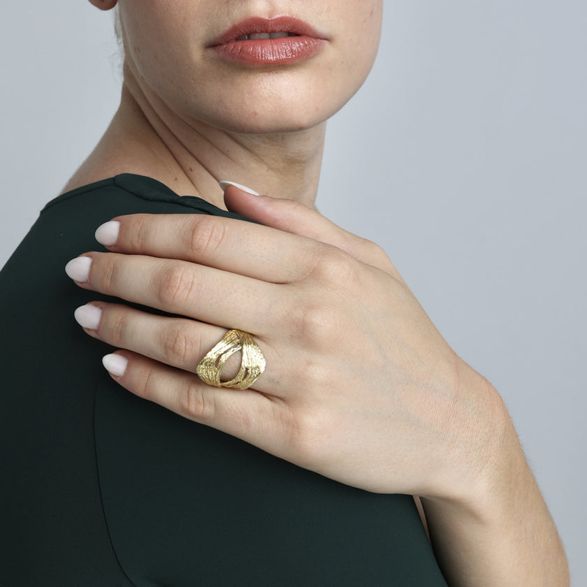 Handmade gold-tone brass wide band textured statement ring with open oval cutout worn on hand — Novel Ring by Kalliope Jewelry, crafted in Greece