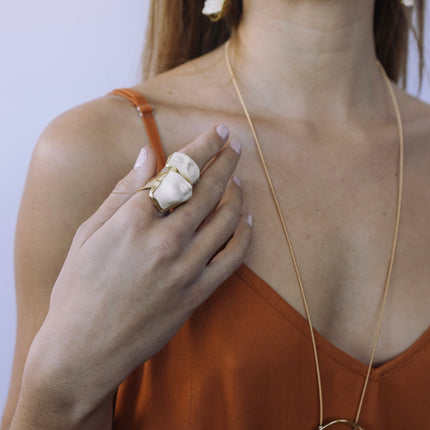 Artisan brass statement ring with white sculpted ceramic face worn on hand — Morpheus Ring by Kalliope Jewelry, crafted in Greece
