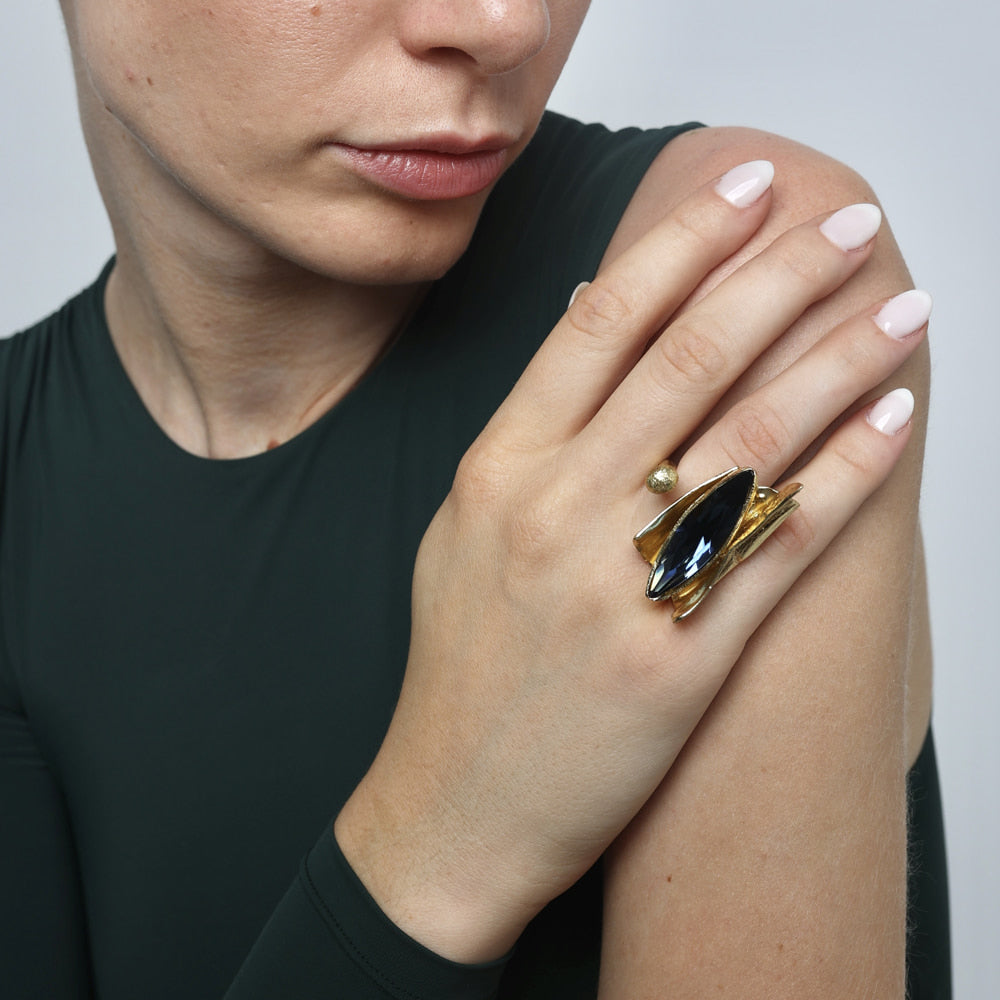 Artisan gold-tone brass statement ring with bold dark marquise crystal in sculptural layered setting worn on hand — Dazzle Ring by Kalliope Jewelry, crafted in Greece
