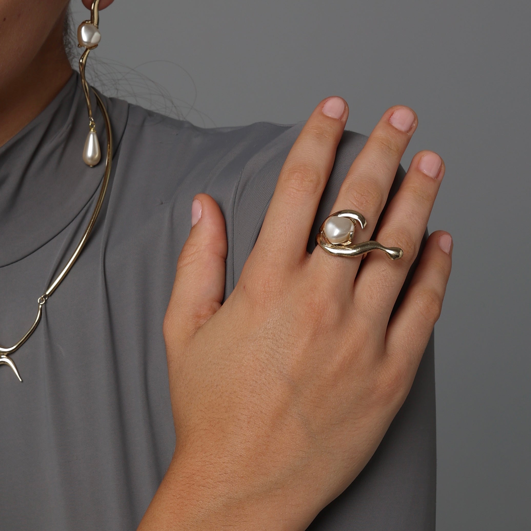 Artisan gold-tone brass fluid wrap ring with baroque pearl worn on hand styled with matching necklace — Swirl Ring by Kalliope Jewelry, crafted in Greece