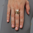 Handmade gold-tone brass double wrap ring with baroque pearl in sculptural prong setting worn on hand — Swirl Layered Ring by Kalliope Jewelry, crafted in Greece