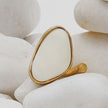 Elemental Pebble Ring flat lay — handmade brass elongated ring with pebble shaped stone accent