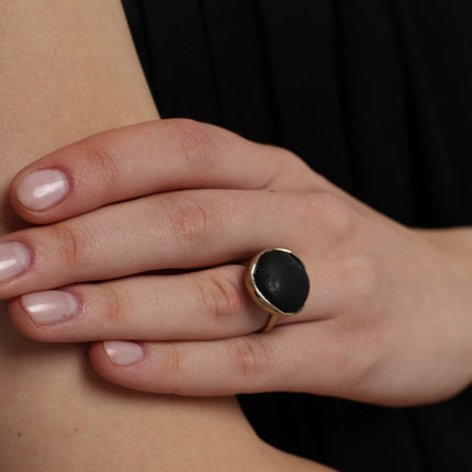 Handmade gold-tone brass ring with large round black stone bezel setting worn on hand — Kiss Ring by Kalliope Jewelry, crafted in Greece