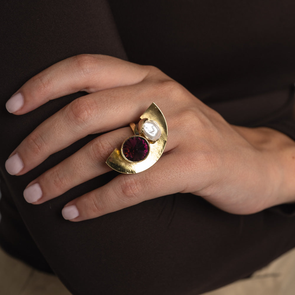 Handmade gold-tone brass half-moon statement ring with deep purple crystal and baroque pearl worn on hand — Orbit Ring by Kalliope Jewelry, crafted in Greece