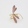 Gold and purple dragonfly-shaped ring on a light gray background