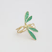 Gold ring with green dragonfly design on a light gray background