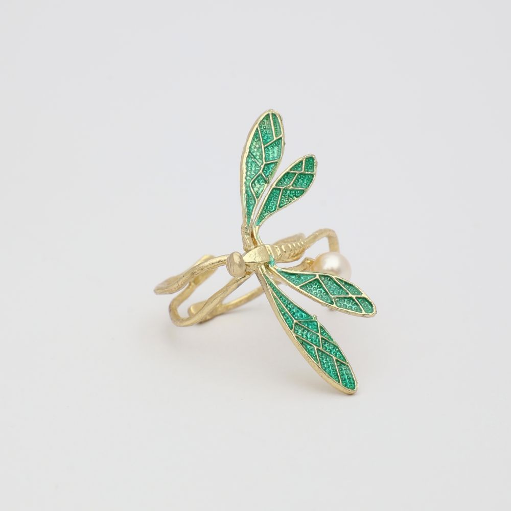 Gold ring with green dragonfly design on a light gray background