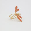 Gold and red leaf-shaped ring on a light gray background