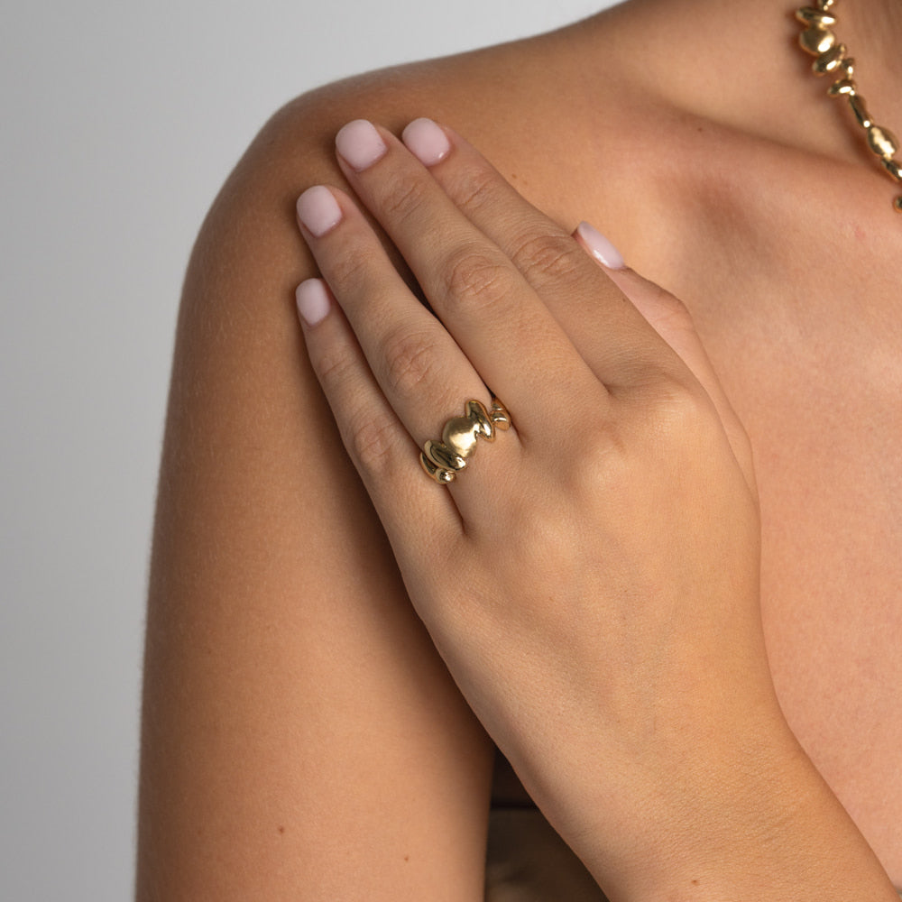 Handmade gold-tone brass adjustable ring with smooth pebble-shaped forms worn on hand — Tame Ring by Kalliope Jewelry, crafted in Greece
