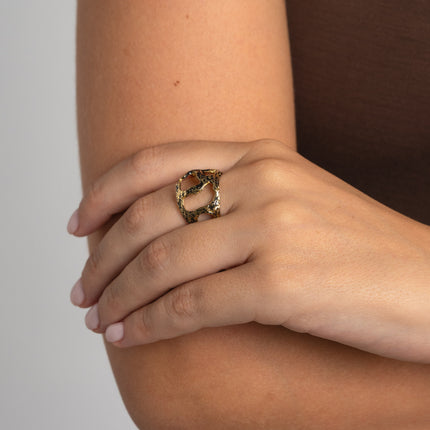 Handmade gold-tone brass open-cut sculptural statement ring with raw textured band worn on hand — Gloomy Ring by Kalliope Jewelry, crafted in Greece