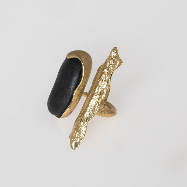 Gold ring with a black stone on a light gray background
