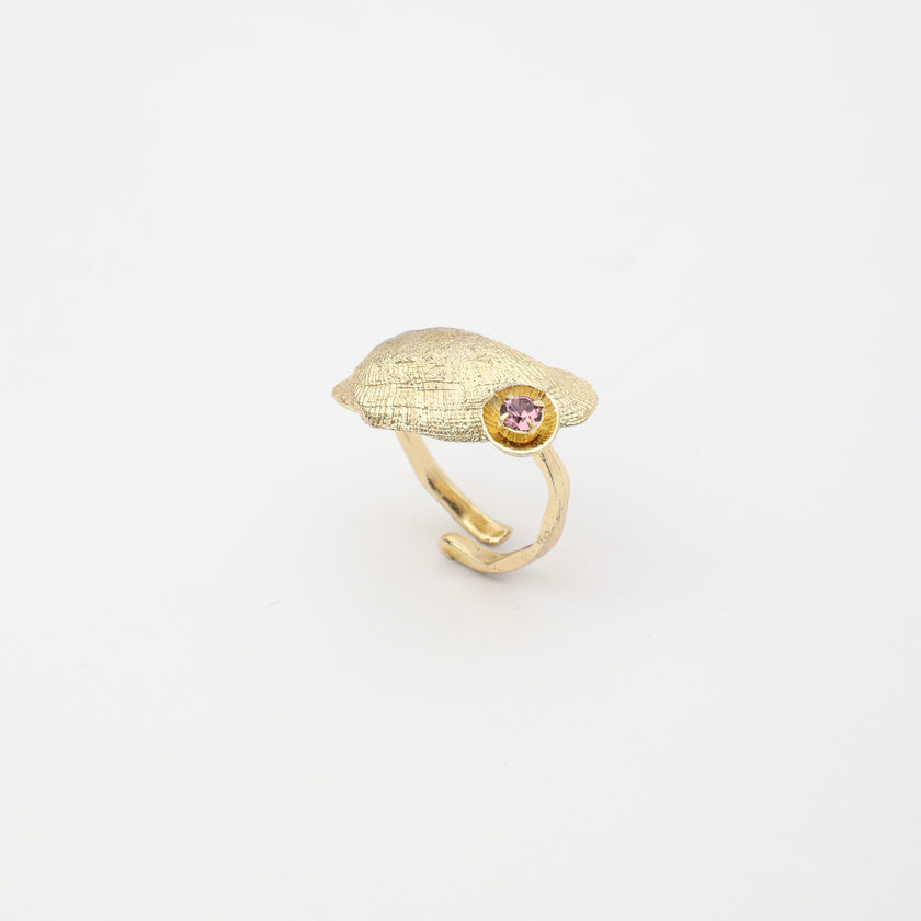 Limpet Ring — handmade brass adjustable ring with textured shell disc and gemstone detail on white background