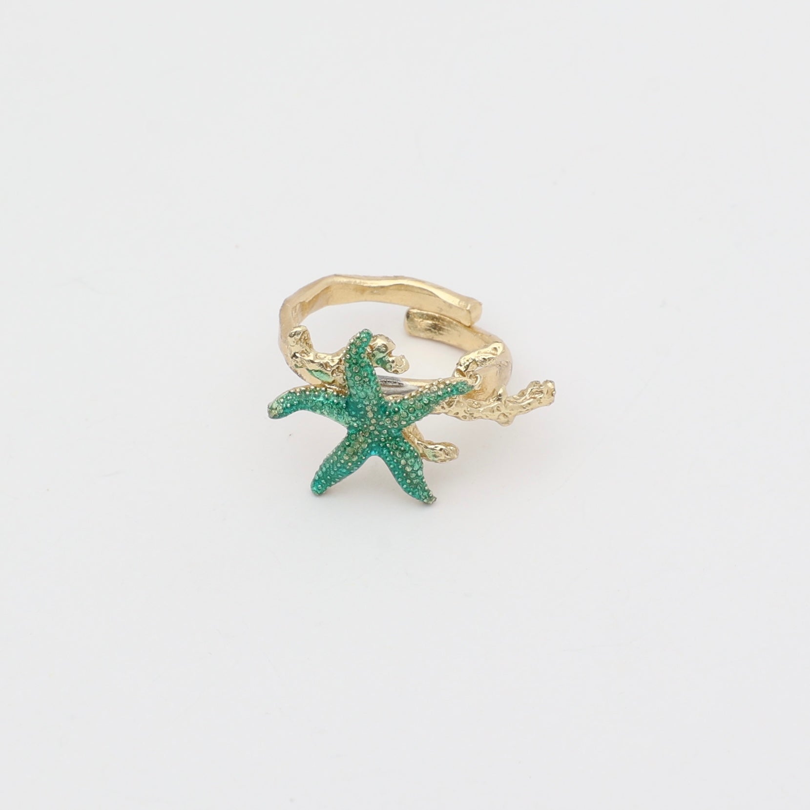 Astel Ring close-up — handmade brass ring with faceted crystal stone set between starfish and coral detail
