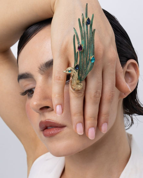 Model wearing the Peacock cocktail ring with green patina feathers and blue, purple and turquoise teardrop crystals, Savage Flora