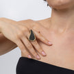 Woman wearing handmade crystal statement ring with elongated asymmetric gold frame on the index finger